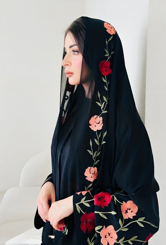 Close-up detail of luxury abaya featuring vibrant floral embroidery with roses and botanical motifs on premium black fabric