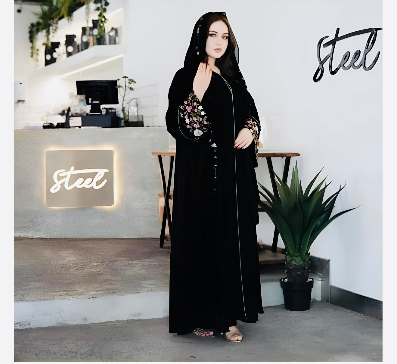 Woman wearing elegant premium abaya with floral embroidery in modern home setting showcasing modest yet stylish Islamic dress