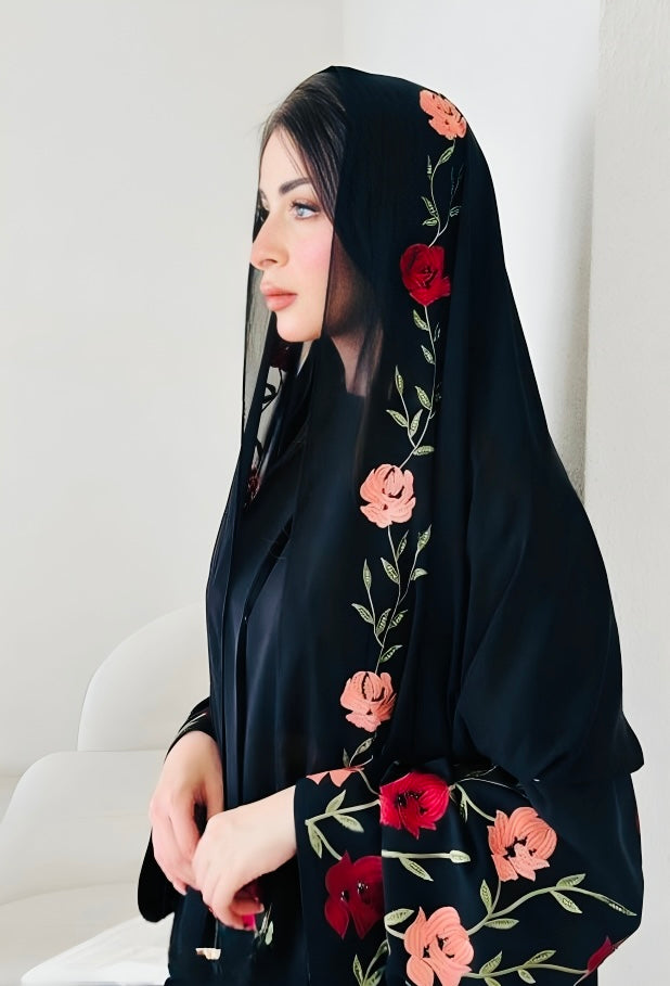 Close-up detail of luxury abaya featuring vibrant floral embroidery with roses and botanical motifs on premium black fabric